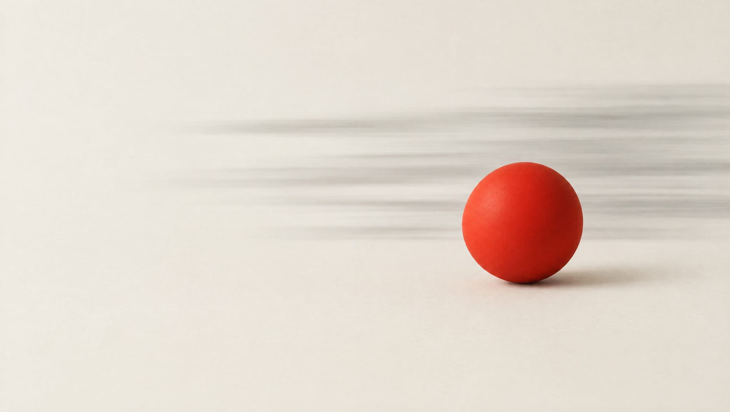 A red sphere resting still while grey motion streaks pass behind it